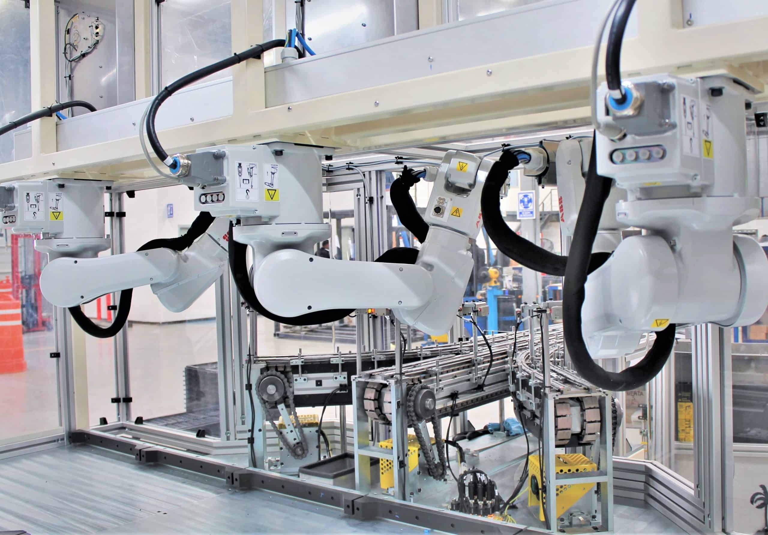 Three ABB robots mounted on a top-down position used to feed components from a conveyor and into a machine.